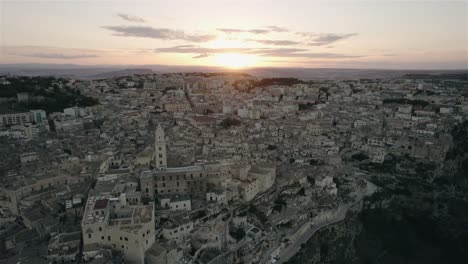 Drone-flying-towards-the-old-white-city-of-Matera-at-sunset-in-south-Italy-in-4k
