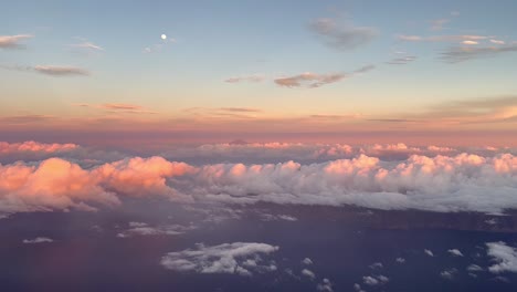 Side-view-from-the-cabin-of-a-commercial-plane-in-flight-at-sunset-flying-over-the-clouds