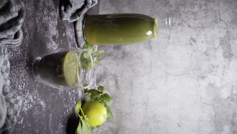 Vertical-video-of-male-hand-putting-glas-of-green-smoothie-or-juice-on-table