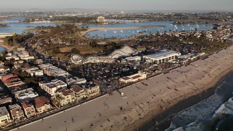 Drone-shot-of-Mission-Bay-in-San-Diego,-California-featuring-the-infamous-Belmont-Park-Giant-Dipper-Roller-Coaster