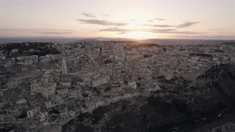 Drone-flying-sideways-and-a-bit-forwards-filming-the-old-white-city-of-Matera-at-sunset-in-south-Italy-in-4k