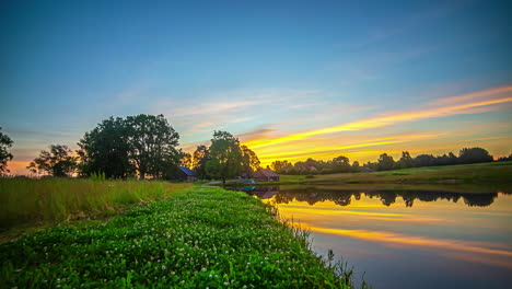 Green-river-banks-at-sunrise-with-colorful-clouds-reflecting-on-water-surface