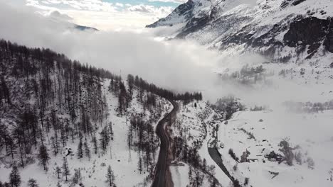 Aerial-landscape-view-of-snow-covering-a-mountain-valley-in-Valle-D'Aosta,-in-the-italian-alps,-in-winter