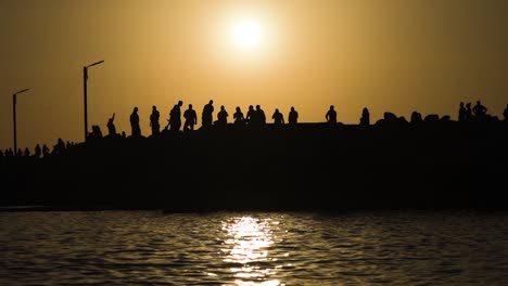 Silhouette-Einer-Gruppe-Von-Menschen,-Die-Bei-Sonnenuntergang-Auf-Dem-Seedock-Spazieren-Gehen