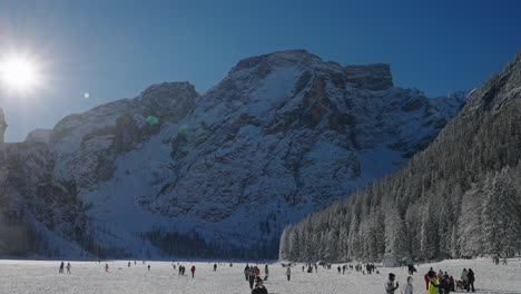 Vista-Panorámica-De-La-Gente-Caminando-Sobre-La-Superficie-Congelada-Del-Lago-Braies,-En-Los-Dolomitas,-Alpes-Italianos