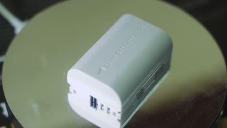 A-rotating-close-up-shot-of-a-white-lithium-camera-battery,-slow-motion-4K