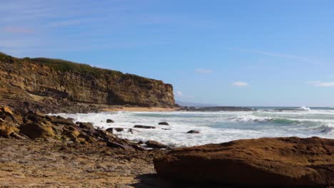 Ocean-meeting-a-cliff-with-waves-hitting-the-rocks-on-a-sunny-day