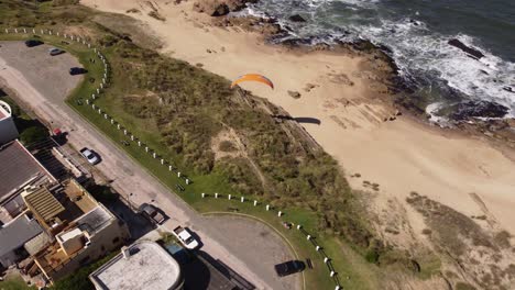 Tourist-enjoying-paragliding-from-beachside-cliffs-at-La-Pedrera-village-on-Atlantic-Coast,-Uruguay