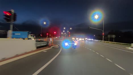 Rear-facing-night-driving-point-of-view-POV-for-interior-car-scene-green-screen-replacement---turning-through-a-well-lit-major-intersection-with-traffic-lights