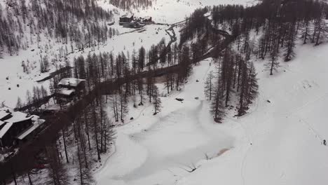 Aerial-view-over-a-frozen-mountain-lake-in-Valle-D'Aosta,-in-the-Italian-Alps,-in-winter