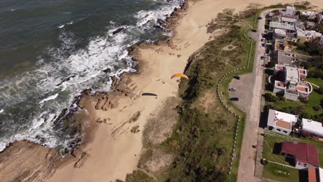 Luftaufnahmen-Von-Touristen,-Die-Gleitschirmfliegen-Von-Den-Klippen-Am-Strand-Im-Dorf-La-Pedrera-An-Der-Atlantikküste-In-Uruguay-Genießen