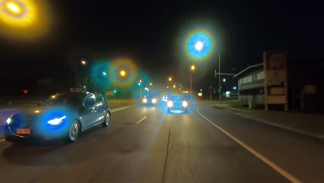 Rear-facing-night-driving-point-of-view-POV-for-interior-car-scene-green-screen-replacement---rush-hour-evening-traffic-on-a-suburban-dual-lane-road-and-stopping-at-traffic-lights