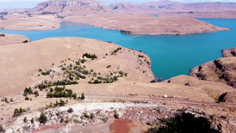 Aerial-drone-shot-rising-up-and-panning-to-reveal-a-scenic-view-of-the-Driekloof-Dam,-its-blue-waters-adding-contrast-to-the-vast-land-which-surround-the-dam,-Free-State,-South-Africa