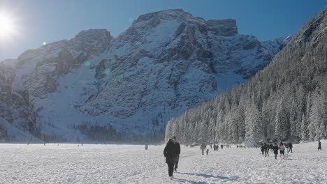 Landscape-view-of-tourists-walking-on-the-frozen-surface-of-Lake-Braies,-in-the-Dolomites,-Italian-Alps