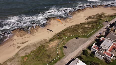 Aerial-shot-of-Paraglider-flying-over-La-Pedrera-Beach-in-Uruguay,-South-America-4K
