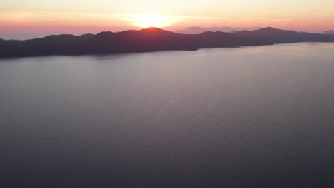 Croatian-coastal-island-in-Adriatic-sea-with-bright-fiery-sunset,-aerial