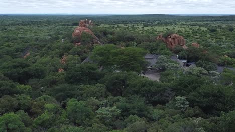 Aerial-drone-shot-approaching-a-remote-bush-camp-resort-situated-in-the-vast-lush-green-African-savanna,-South-Africa