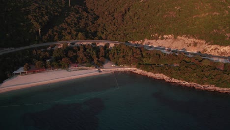Red-sunlight-from-sunset-shining-on-Croatia-coast-at-Veliki-žal-beach,-aerial
