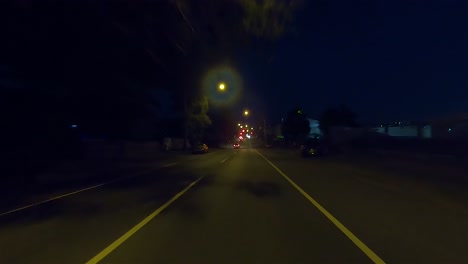 Rear-facing-night-driving-point-of-view-POV-for-interior-car-scene-green-screen-replacement---long-straight-suburban-city-street-with-moderate-traffic-passing-by
