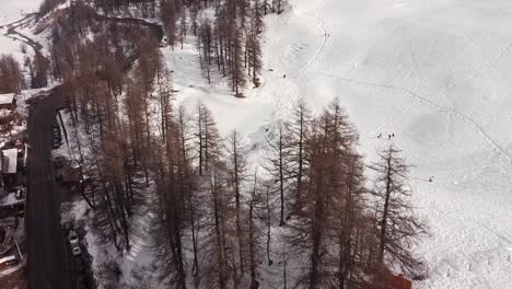 Aerial-view-over-a-frozen-lake-in-a-mountain-valley-in-Valle-D'Aosta,-in-the-Italian-Alps,-in-winter