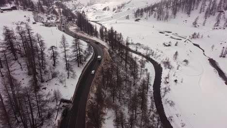 Aerial-view-of-a-road-through-snow-capped-mountains-in-Valle-D'Aosta,-in-the-italian-alps,-in-winter