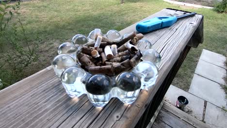 An-ashtray-full-of-cigarette-butts-sitting-on-a-wooden-railing-outside-of-a-house-in-the-front-yard-during-the-daytime
