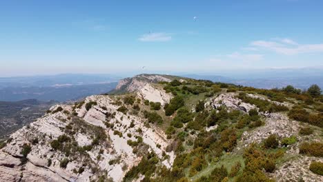 Ager,-Lerida,-Katalonien,-Spanien---Luftdrohnenansicht-Von-Parasailingtouristen-Auf-Der-Spitze-Des-Berges-Mit-Wunderschönem-Blick-über-Das-Grüne-Tal-Und-Die-Schlucht-Des-Mont-Rebei---Ultimative-Freiheit