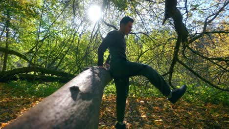 Young-Man-Jumping-Over-A-Tree-Trunk-In-The-Forest-During-Fall-Season--Slow-motion