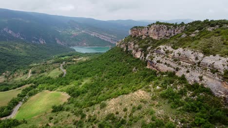 Congost-de-Mont-Rebei-Canyon-at-Ager,-Catalonia-and-Aragon,-Spain---Aerial-Drone-View-of-the-Steep-Rocky-Cliffs,-Green-Valley-and-Blue-Emerald-Lake