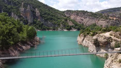 Congost-de-Mont-Rebei-Canyon-at-Ager,-Catalonia-and-Aragon,-Spain---Aerial-Drone-View-of-the-Bridge-over-Blue-Emerald-Noguera-Ribagorzana-River-Lake