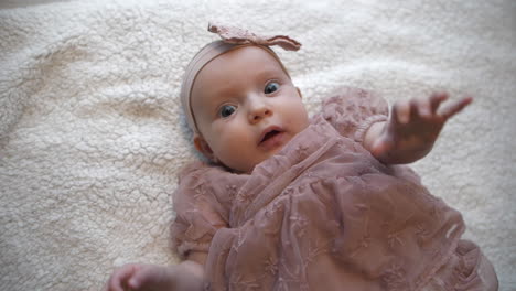 Top-Down-view-Of-Dressed-up-Baby-Girl-on-Blanket,-slow-motion