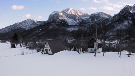 AERIAL---Beautiful-snowy-winter-on-a-farm,-Kolasin,-Montenegro,-truck-left