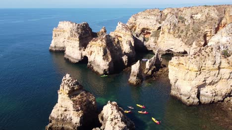 Ponta-Da-Piedade,-Lagos,-Algarve---Aerial-Drone-View-of-Kayakking-Tourists-and-the-Coastline-with-Rocky-Cliffs