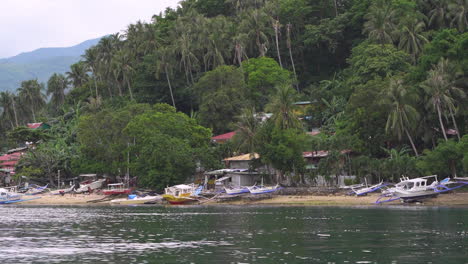 Vista-Desde-Un-Barco-Que-Entra-En-Una-Isla-De-Pequeños-Barcos-Pesqueros-Estacionados-En-La-Playa