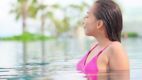Close-up-of-a-beautiful,-confident-woman-enjoying-the-view-from-the-swimming-pool
