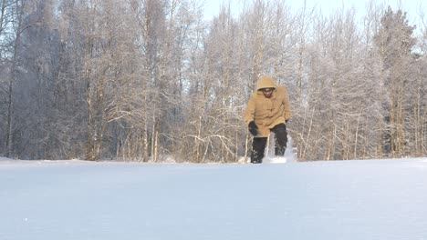 Man-walks-toward-and-past-camera-through-deep-snow-in-forest