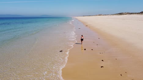 Playa-Comporta-En-La-Costa-Oeste-De-Portugal---Vista-Aérea-De-Drones-De-Una-Chica-Turista-Sola-Caminando-En-La-Playa-De-Arena