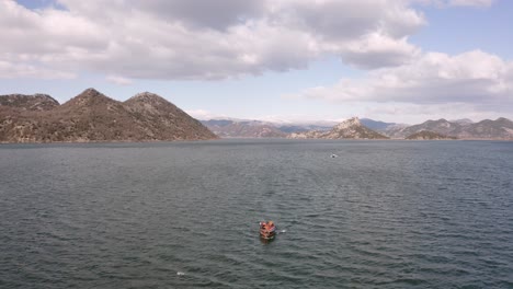 AERIAL---Boat-ride-on-beautiful-Lake-Skadar,-Montenegro,-reverse-reveal