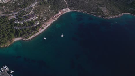 Sailboats-anchored-near-beach-on-Croatian-shore,-aerial