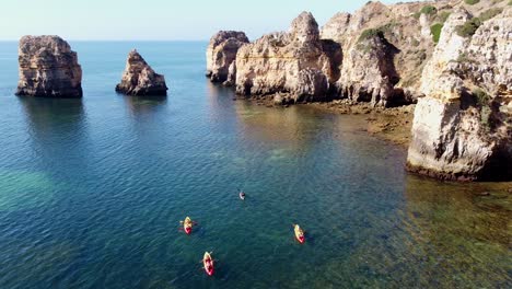 Ponta-Da-Piedade,-Lagos,-Algarve---Aerial-Drone-View-of-Kayakking-Tourists-and-the-Rocky-Coastline-with-Beautiful-Cliffs