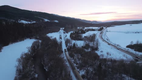 Luftaufnahme-über-Den-Zug,-Der-Durch-Die-Winterschneelandschaft-Im-Tatra-nationalpark-Gegen-Sonnenuntergangshimmel-Fährt