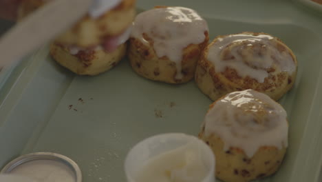 Close-up-slow-motion-shot-of-a-person-frosting-fresh,-homemade-cinnamon-rolls