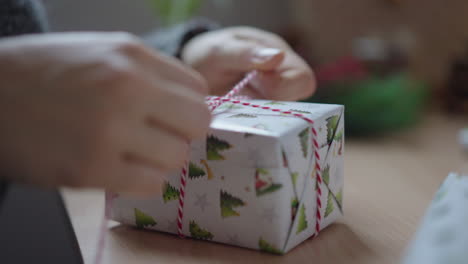 Hände-Binden-Band-Um-Ein-Verpacktes-Weihnachtsgeschenk,-Nahaufnahme