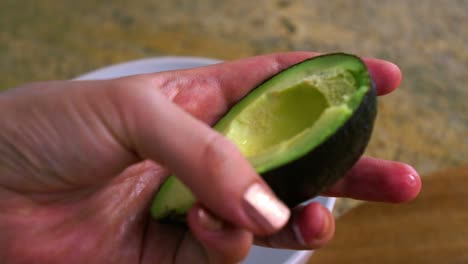 Person-Scooping-Ripe-Avocado-With-A-Spoon-In-The-Kitchen