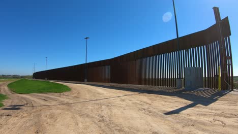POV-Trasero-Conduciendo-En-La-Vía-De-Servicio-Lejos-Del-Muro-Fronterizo-Entre-Estados-Unidos-Y-México
