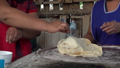 Mexican-cooks-flipping-a-tlayuda-on-a-comal