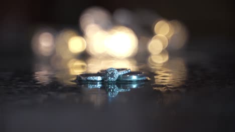 Close-up-rack-focus-to-wedding-rings-on-ice-with-lights-in-the-background