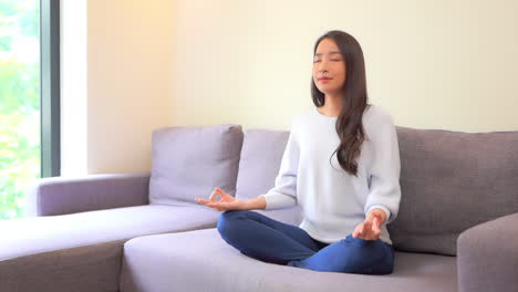 A-lovely-young-woman-sitting-cross-legged-strikes-a-yoga-pose-as-she-meditates