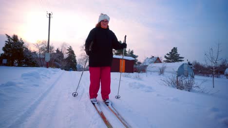 Old-Woman-Skiing-In-Snowscape-Neighborhood-During-Winter-In-Countryside-Of-Lithuania
