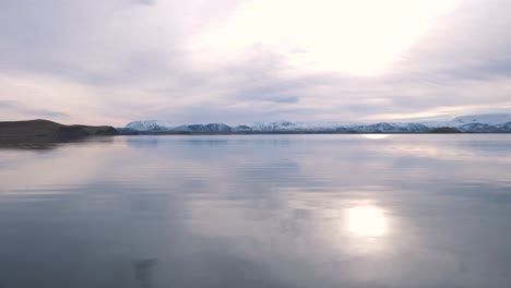Sunrise-over-lake-Myvatn-in-Iceland,-snowy-mountains-beyond-the-shore